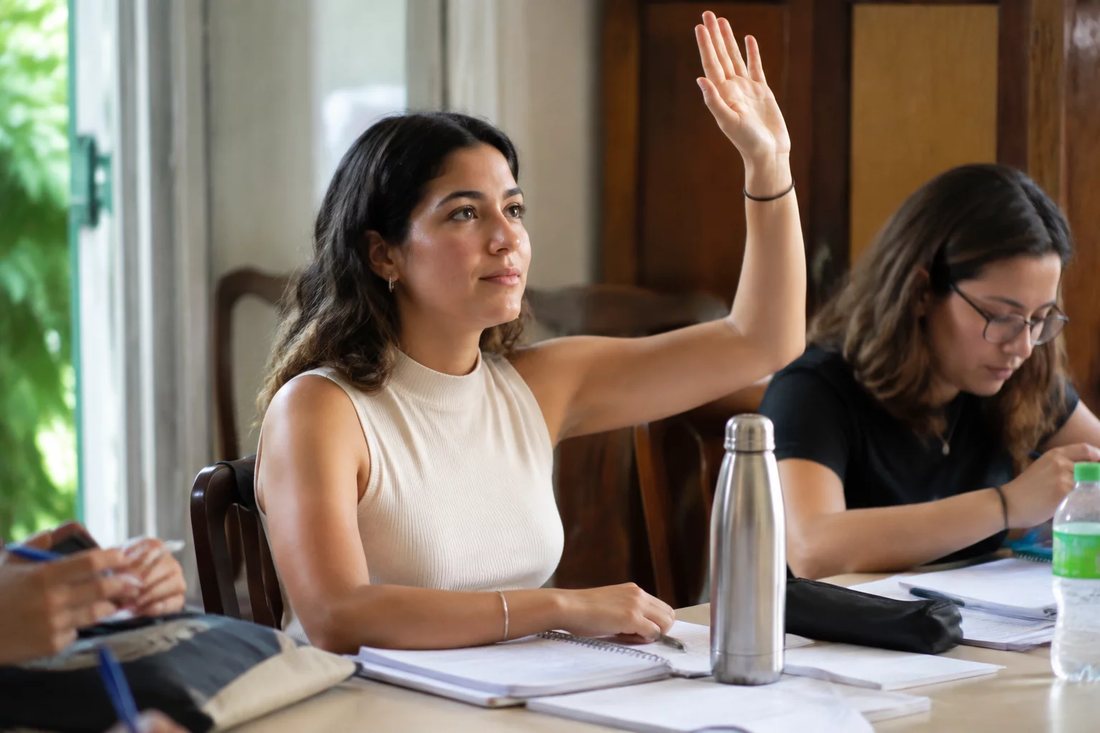 Facilitador de pé apontando para um argumento escrito no quadro durante a sessão